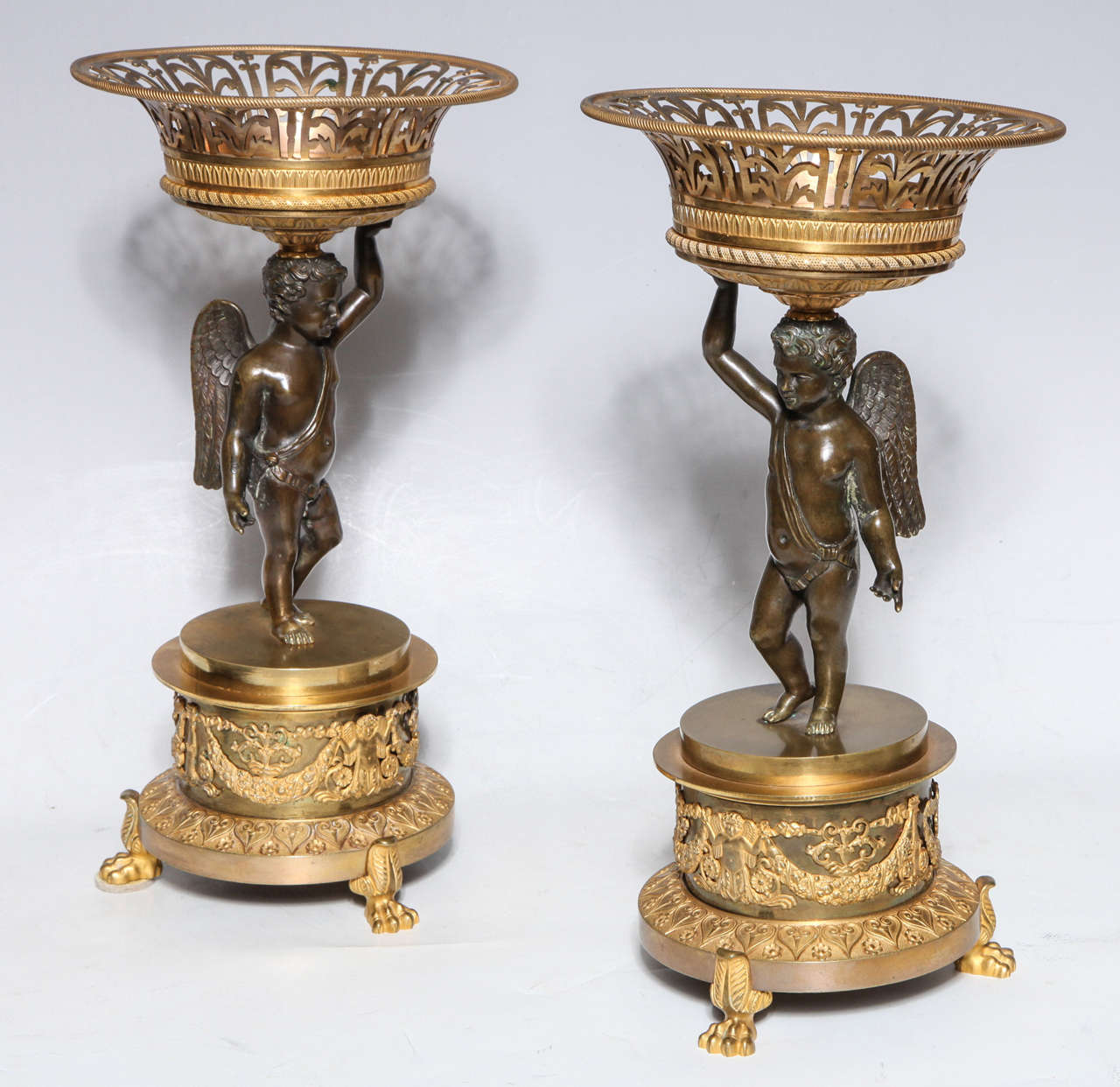 Pair of Russian Empire period gilt and patinated bronze cupid compote centrepieces with gilt bronze filigree baskets. The cupids pose in contrapposto holding two toned gilt bronze filigree baskets on their heads, 

circa 1810.