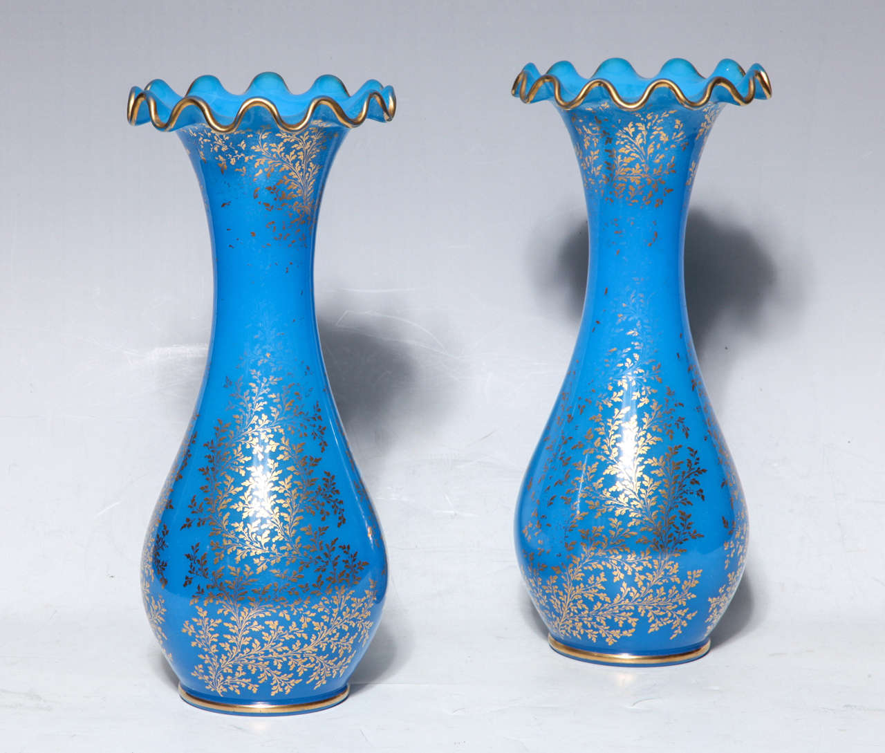 Paire de vases en cristal opalin bleu de Baccarat avec décorations florales en or peint à la main 24 carats et bords ondulés. Pour une paire similaire, veuillez consulter les photos dans le livre sur le Baccarat. Paire de vases en cristal opalin