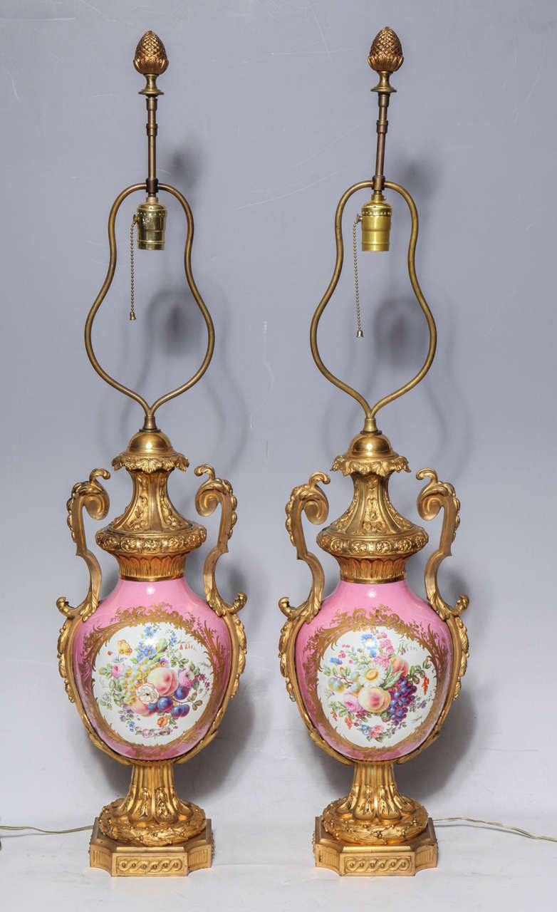 Pair of Louis XVI style French Sevres pink porcelain and dore bronze-mounted vases or lamps. One side is painted with pastoral love scenes in the vein of Watteau, the famous 18th century artist. The reverse is painted with an abundance of life-like