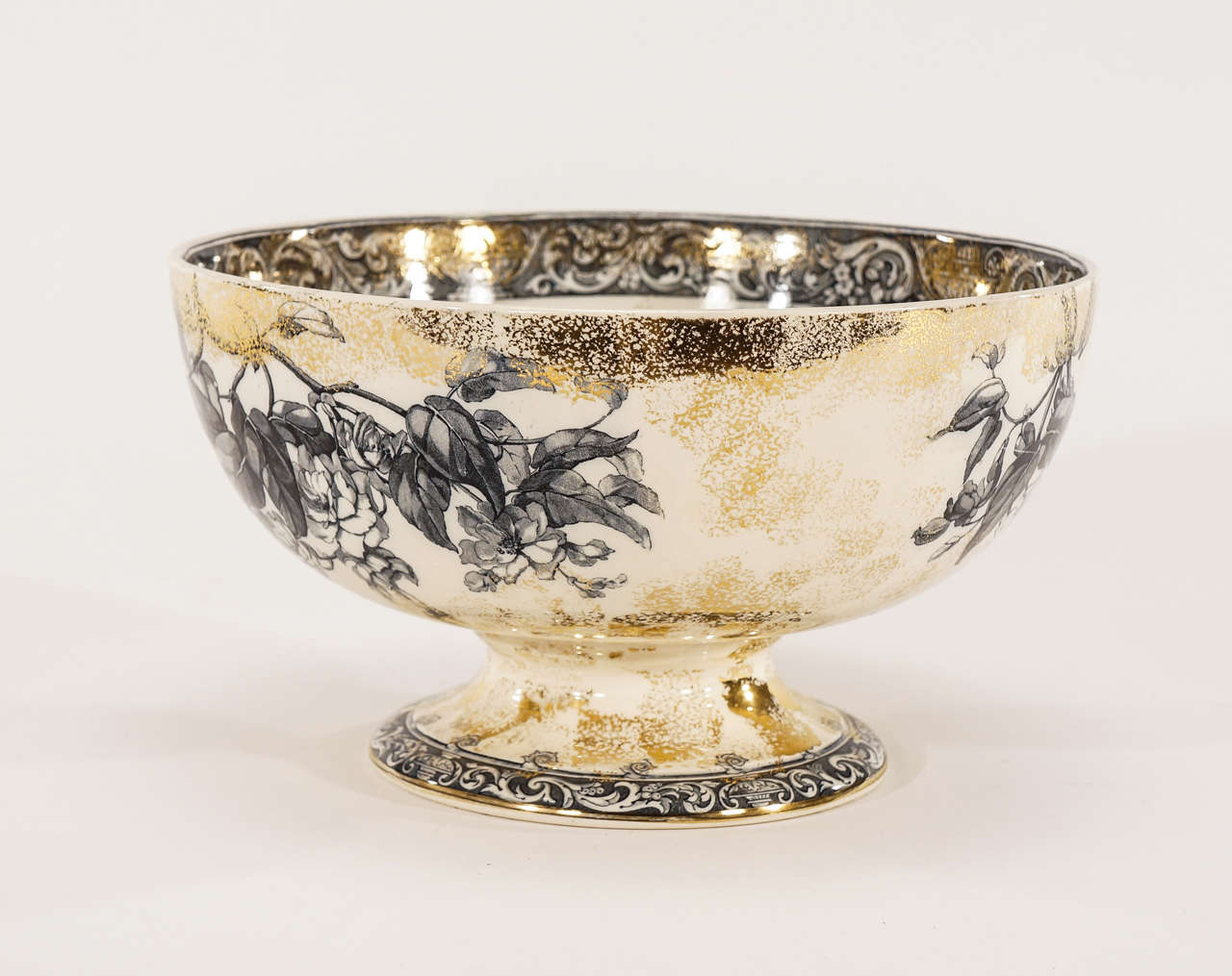 Parfait comme centre de table, ce bol à punch sur pied Doulton du XIXe siècle est magnifiquement décoré d'un motif botanique dans un ton bleu d'encre sur fond ivoire et rehaussé d'émaux dorés. Les bordures sont ornées d'un motif de transfert