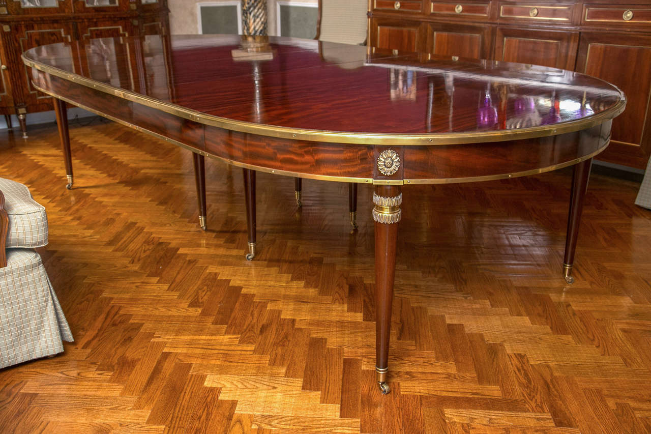 Finest Maison Jansen three-leaf dining table. This one of a kind circular flame mahogany dining table is the finest example of this acclaimed designers workmanship. The heavy full bronze wheeled casters leading to a set of rounded Louis XVI styled