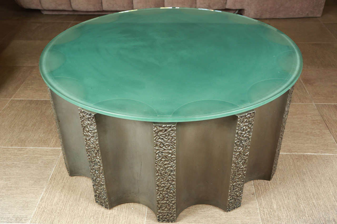 Impressive drum shaped coffee table by Steve Chase. The drum is fluted and has a dark bronze-gray finish. The glass top has a beveled edge.