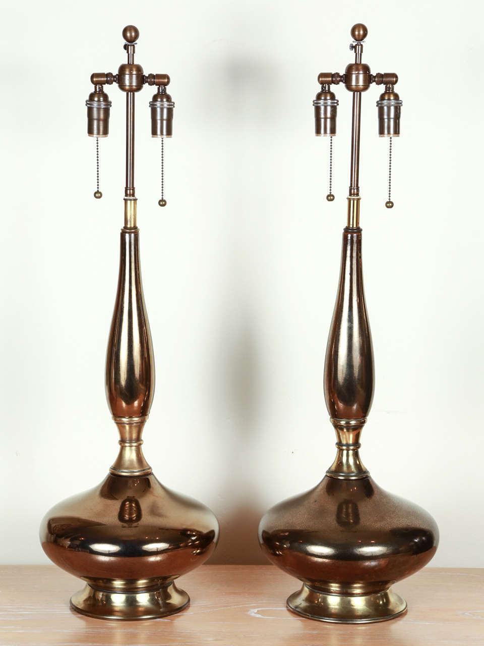 Pair of exotic ceramic urn shaped lamps with brass appointments. The glaze is a golden bronze with crackling, and they are newly rewired with  bronze finished double clusters