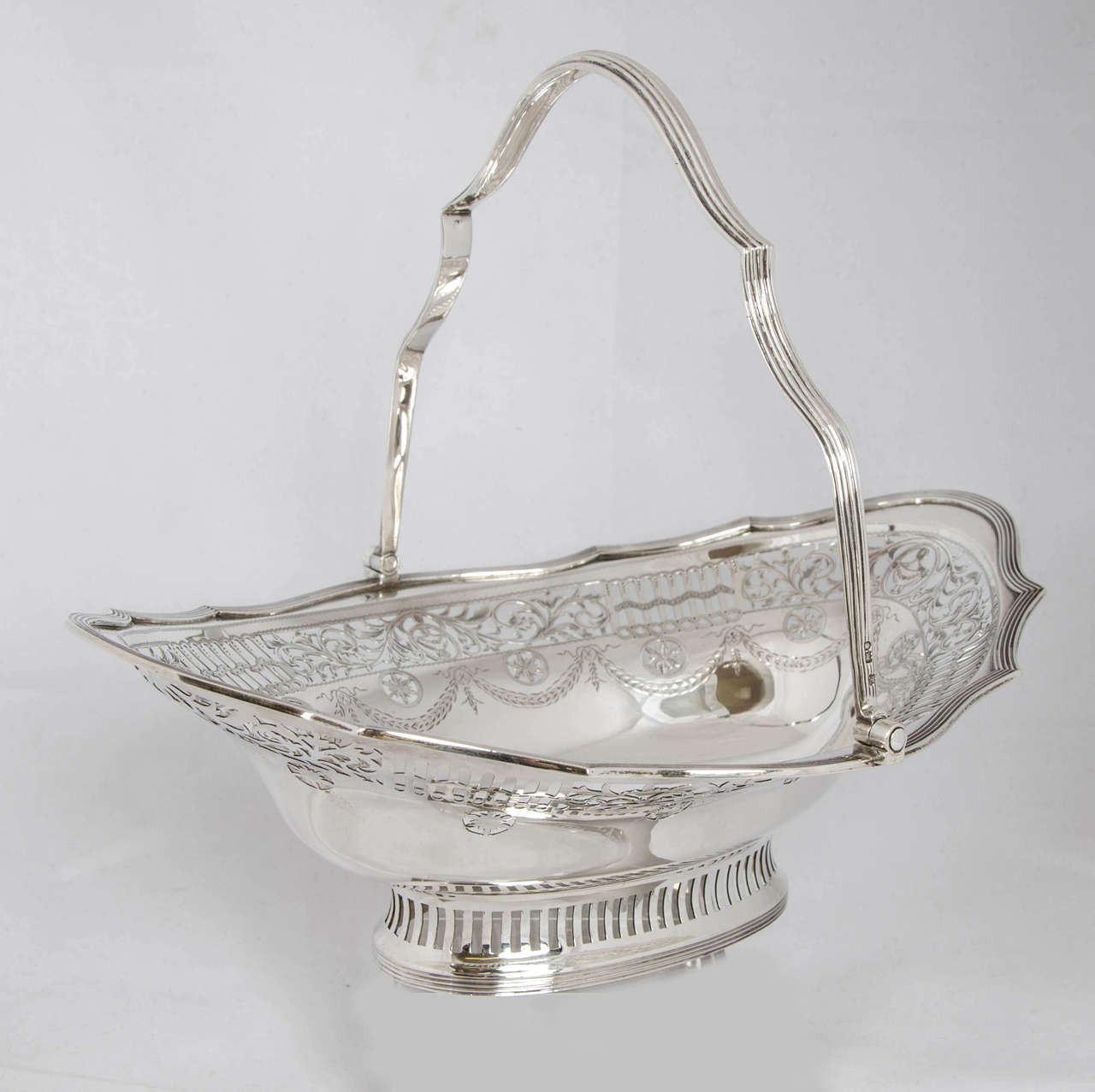 An Edwardian silver cake basket of classical Adams design. The basket was made in London in 1906 by Charles Stuart Harris, and retailed by The Bond Street firm of Thomas. It is 13