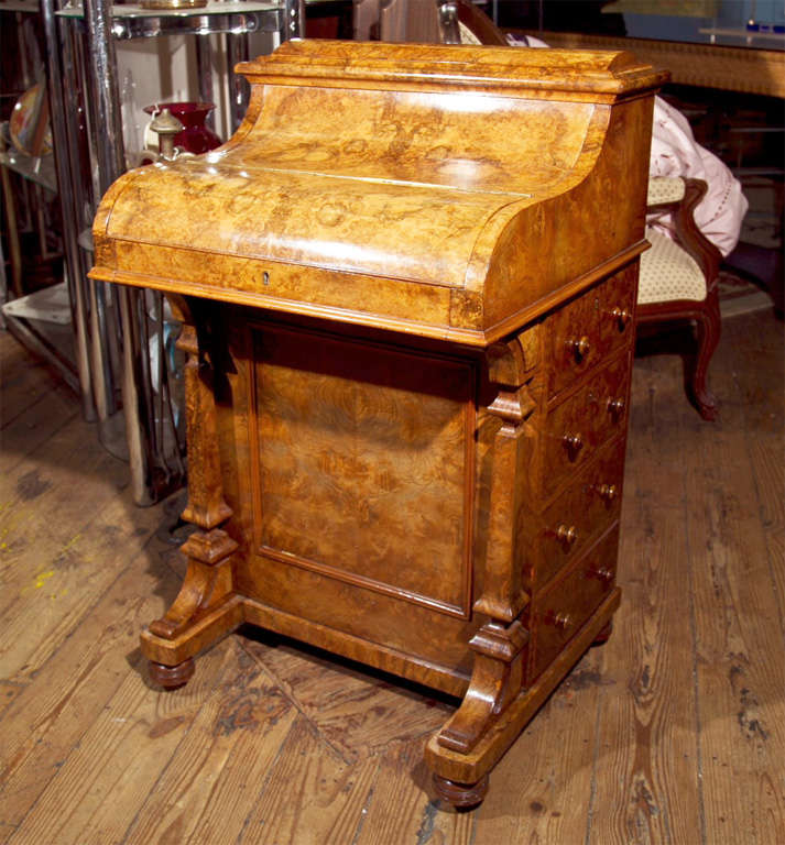 A FINE PIANO TOP BURL WALNUT DAVENPORT. THE POP UP STATIONARY COMPARTMENT ABOVE HINGED TOP WITH FITTED INTERIOR -FOUR DRAWERS WUTH KNOB HANDLES OPPOSED BY FOUR DUMMY DRAWERS. RAISED ON SHAPED SUPPORTS- IN EXTREMELY FINE CONDITION.