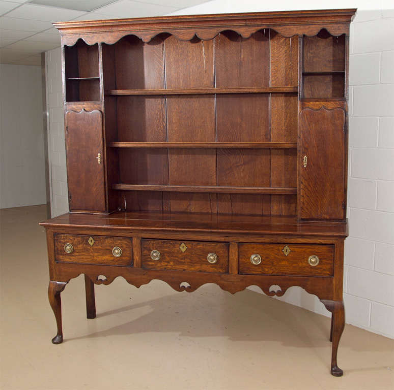 ENGLISH MADE ANTIQUE WELSH DRESSER IN TWO PARTS. TOP HAS CLOSED BACK WITH SHELVES AND SPICE CUPBOARDS.. BASE HAS THREE DRAWERS..OVERALL SHAPED APRON AND ENDS ON CABRIOLE LEGS WITH PAD FEET.. AUTHORIRY  DOYLE GALLERIES, NYC.