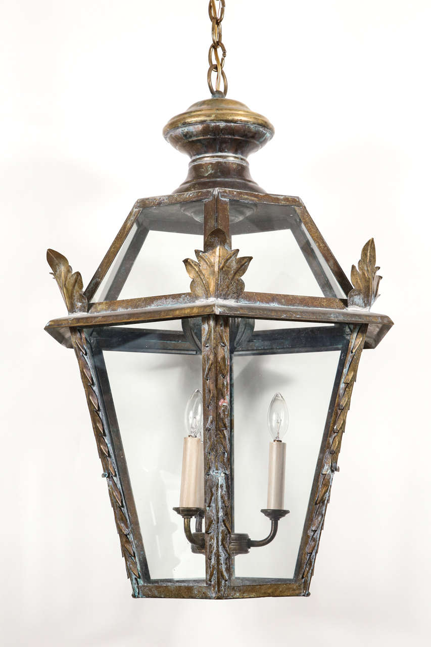 Hexagon shaped antique lanterns with naturally patinated finish, laurel leaf details and original glass.  Rewired with four candelabra base bulbs.  Chain and canopy are included.