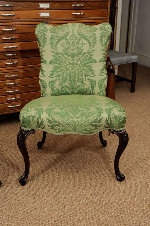 A PAIR OF GEORGE III MAHOGANY SIDE CHAIRS CIRCA 1770 the curved serpentine-upholstered back and overupholstered seats on cabriole legs with leaf-carved knees terminating in scroll toes; upholstered in a green silk damask, one with a paper label