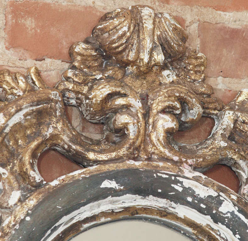 Unique hand carved large Italian mirror.  Beautiful patina consisting of gilded frame with dark blue painted details and gesso showing through.  Absolutely stunning.