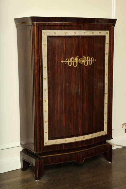 Ce meuble en ébène de macassar possède deux portes entourées d'une bande de galuchat blanc et décorées d'ornements en bronze doré. 

Frechet était directeur de l'Ecoule Boulle à Paris. Il participe de 1921 à 1935 au Salon des Artistes Décorateurs,