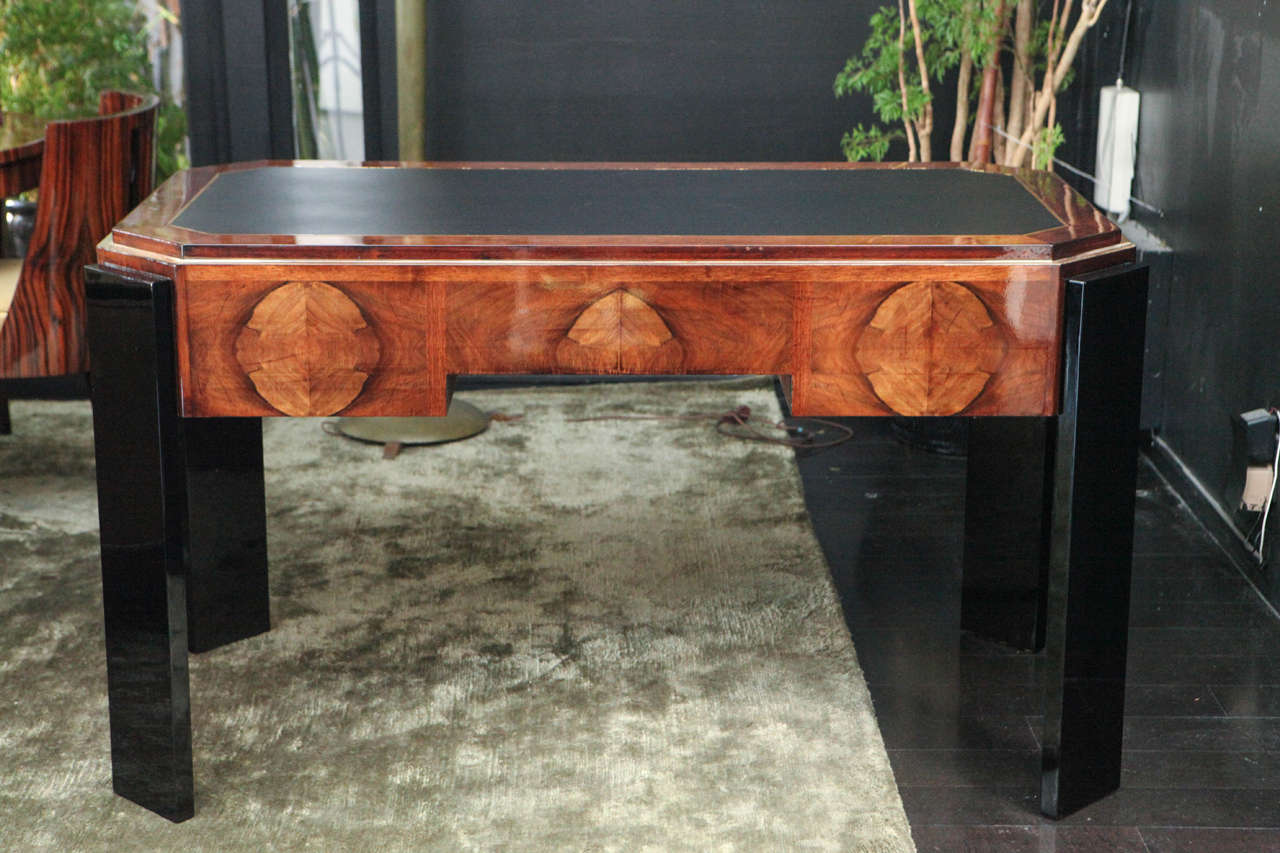 Handsome octagonal Art Deco desk in walnut with black lacquer legs. Gold leaf border and hardware. Black leather desktop with gold leaf detailing. Three drawers in front, middle drawer with key.