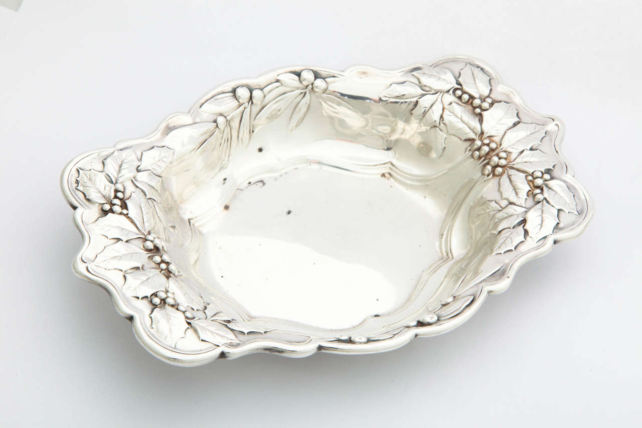 A lovely and festive sterling silver bowl decorated with holly and mistletoe around the edges. This is a perfect bon dish, or could hold a small holiday floral arrangement. 

The bowl was made in circa 1890 by the American Silversmith; Whiting