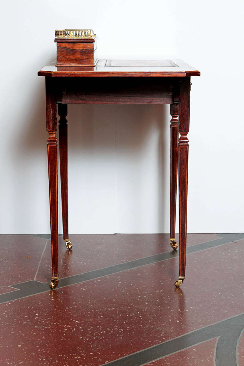 19th century rosewood drop-leaf table or writing desk with satinwood banding and bone inlay with details of special interest. The legs are in casters. The top opens for pen and ink storage. Signed 