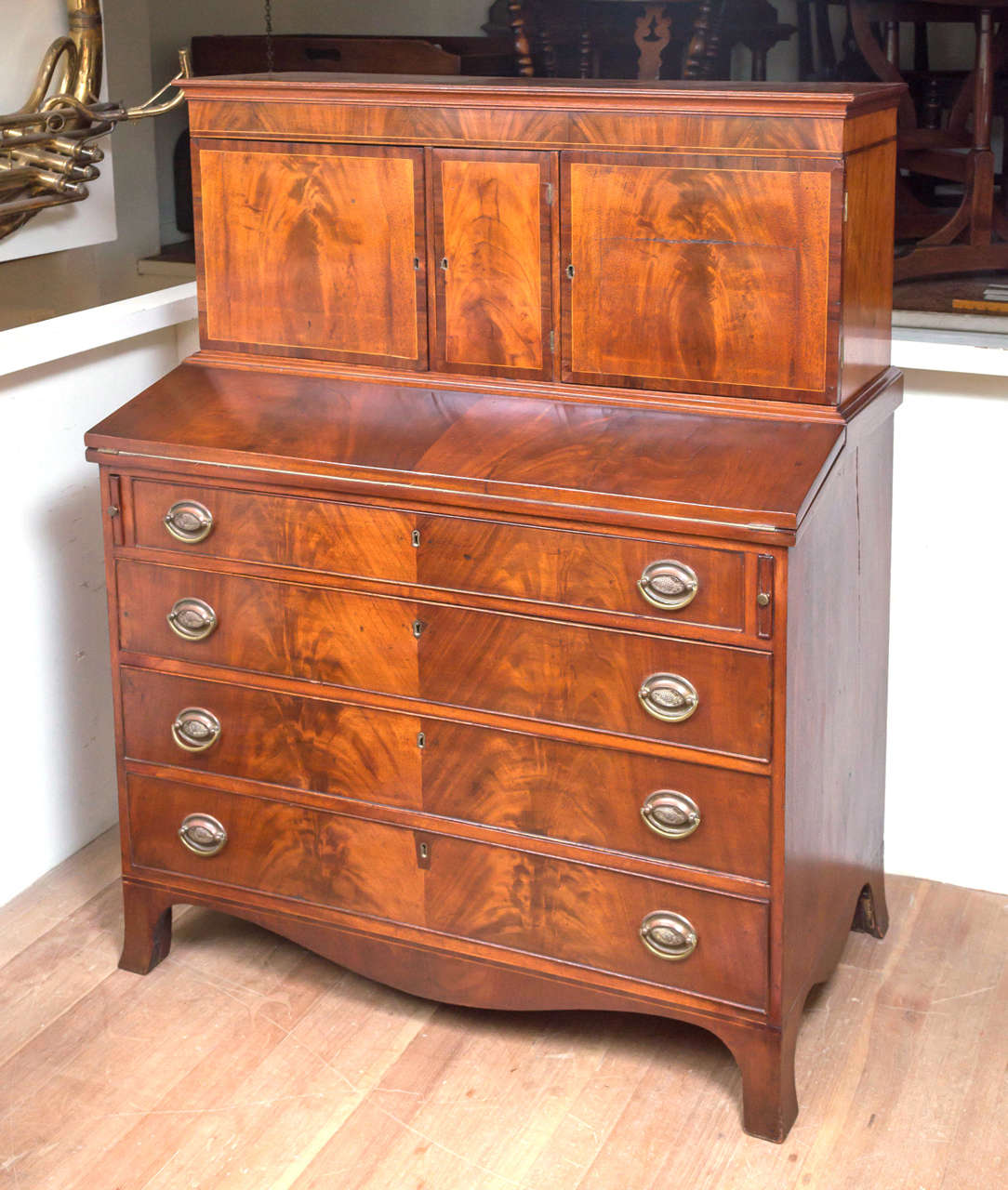 19th century American federal mahogany secretary desk, circa 1815. A fully fitted cabinet sets above the writing surface and four graduated drawers below. Beautiful figured crotch mahogany veneers and crossbanded line inlaid woods on the cabinet.