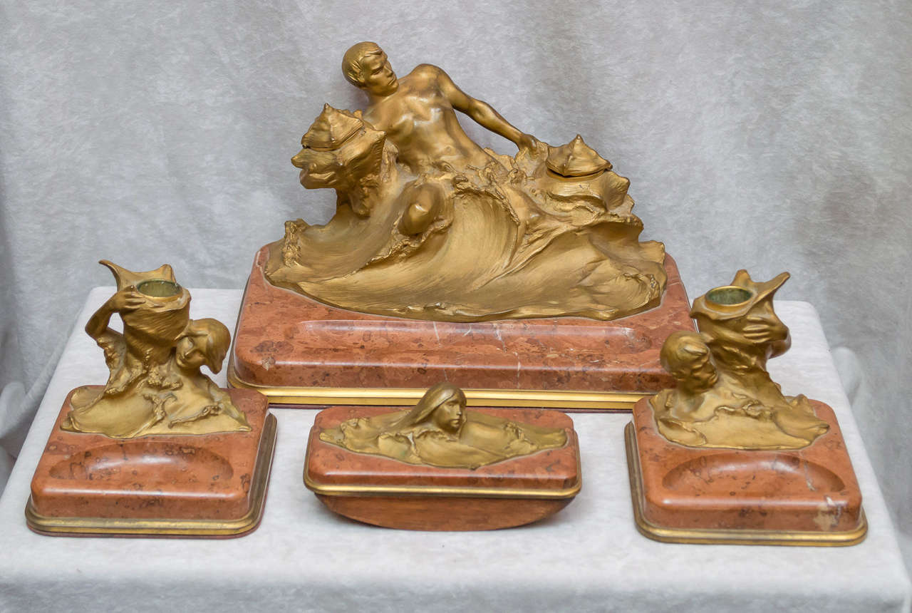 A very unusual Art Nouveau desk set for the astute collector. It is quite rare to see male figures represented in Art Nouveau sculpture. There are four pieces, including an inkwell, a pair of candlesticks, and an ink blotter. The male figure on the