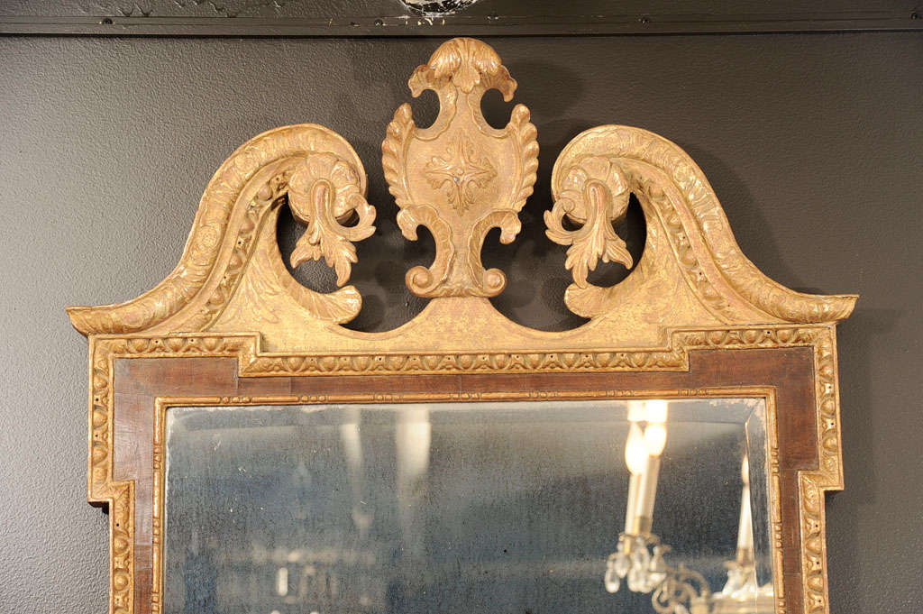 Fine George II walnut and gilt mirror with scrolling broken pediment top centred by cartouche and having carved shells, egg and dart moldings, acanthus leaves and sconce arms.