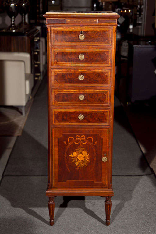 Pair of French Louis XVI style mahogany and satinwood marquetry lingerie chests, each with square beige marble top, over a conforming case fitted with 5 drawers and a cabinet door decorated with ribbon and floral inlaid, raised on tapering bulbous
