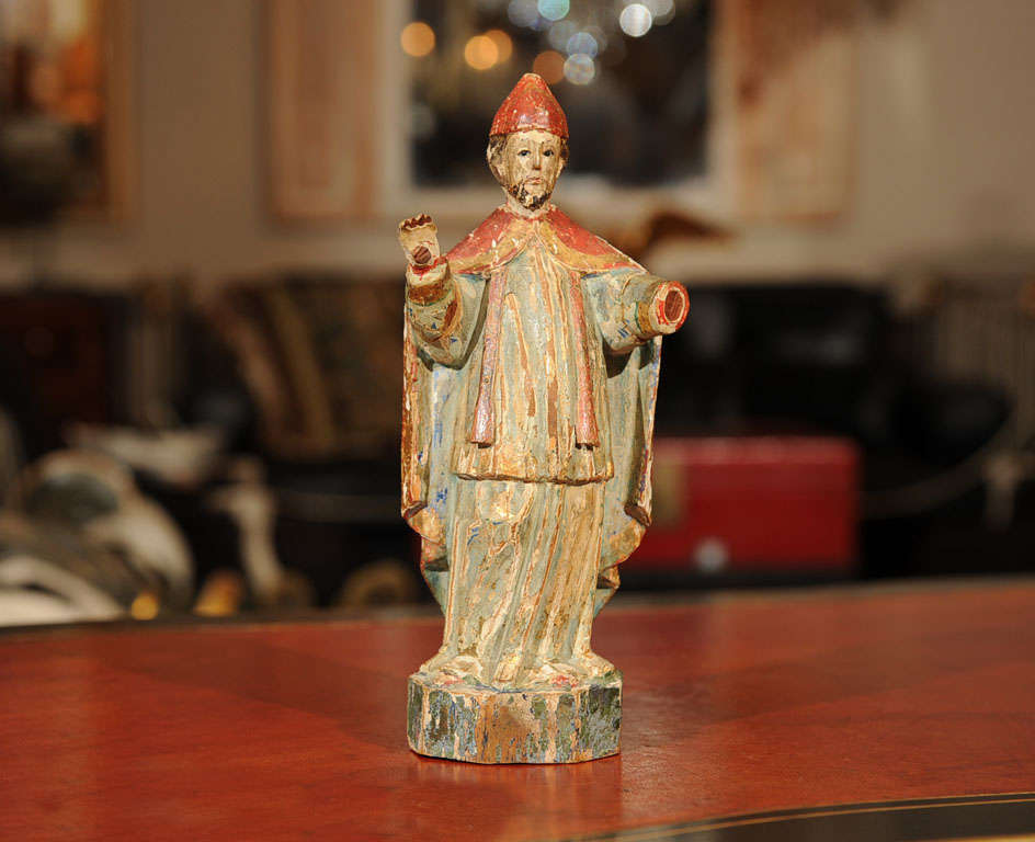 The bearded Bishop wearing the traditional red miter and trimmed red robe, standing in slight contrapposto with arms outstretched before him, raised on a square base.
