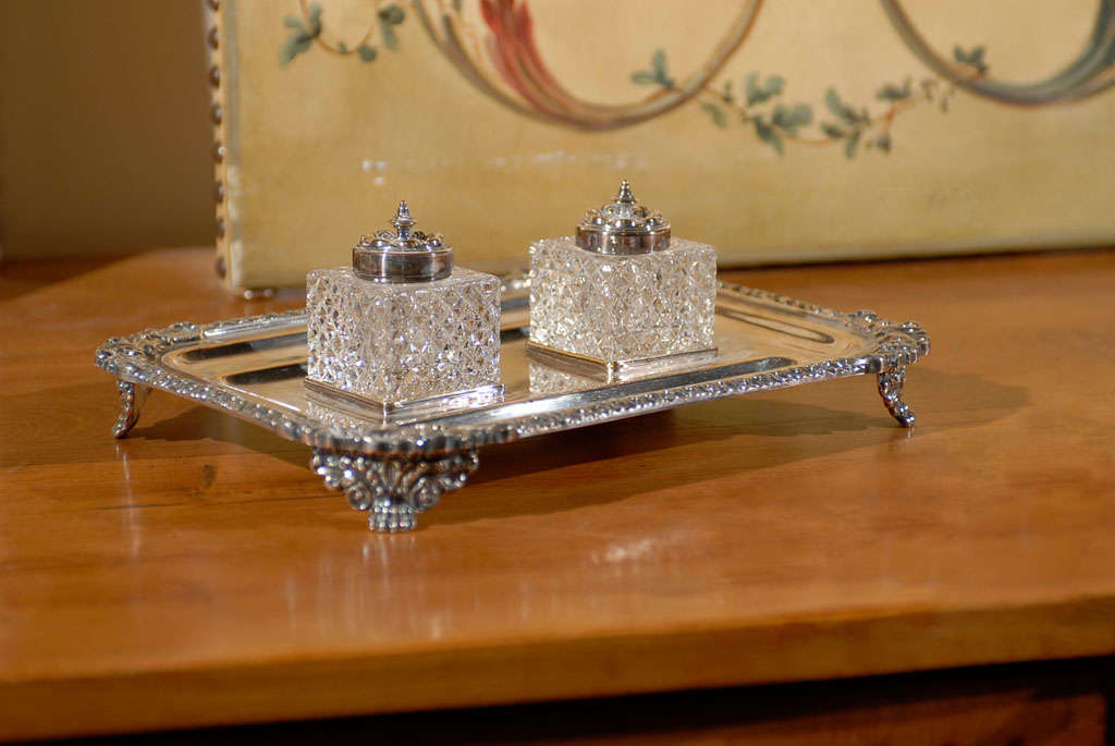 An English stamped silver inkstand from the late 19th century, with two crystal inkwells. Born during the later years of Queen Victoria's reign, this exquisite piece features a silver tray, adorned with delicate motifs on the trim and raised on four