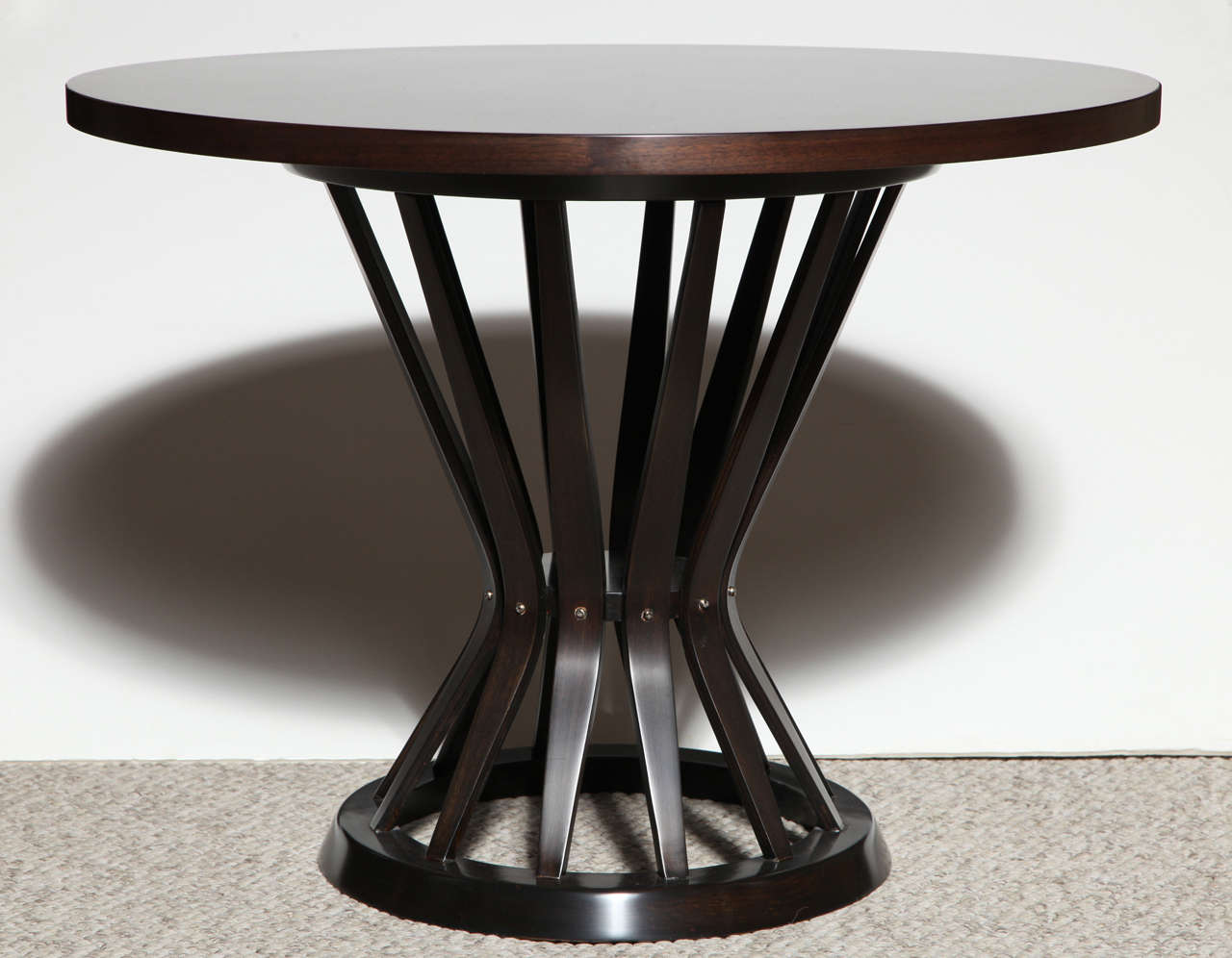 Circular walnut top and mahogany base of tapering, bent wood slats.   one of many iconic Wormley designs.
