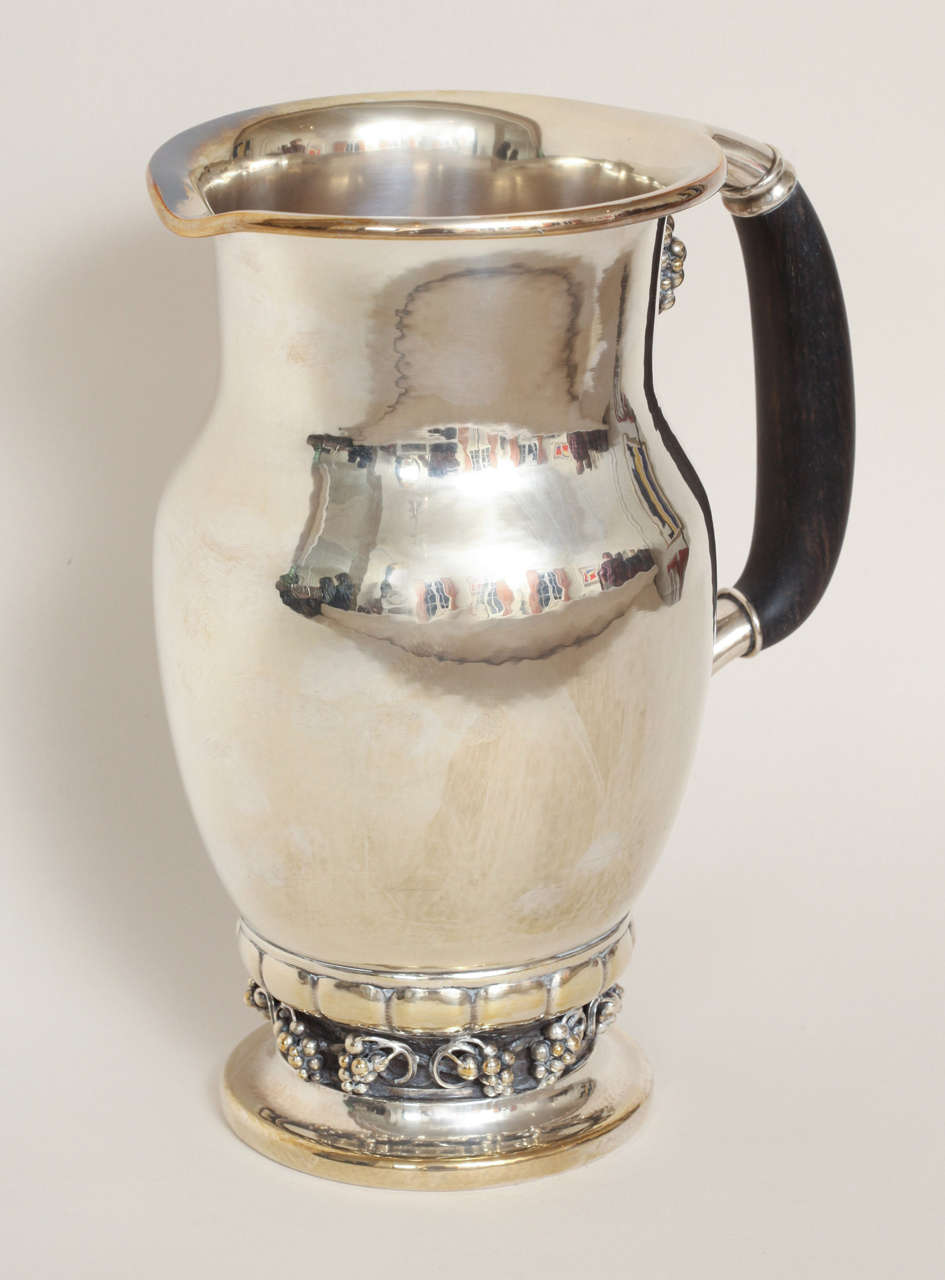 This water pitcher has a bulbous openwork base with stylized grape clusters and ebony handle with attached grape cluster mount.
Hallmarks: Georg Jensen mark for post 1945/ 407 A/ DENMARK/ STERLING

33 ozs. gross

Variety of other Georg Jensen silver