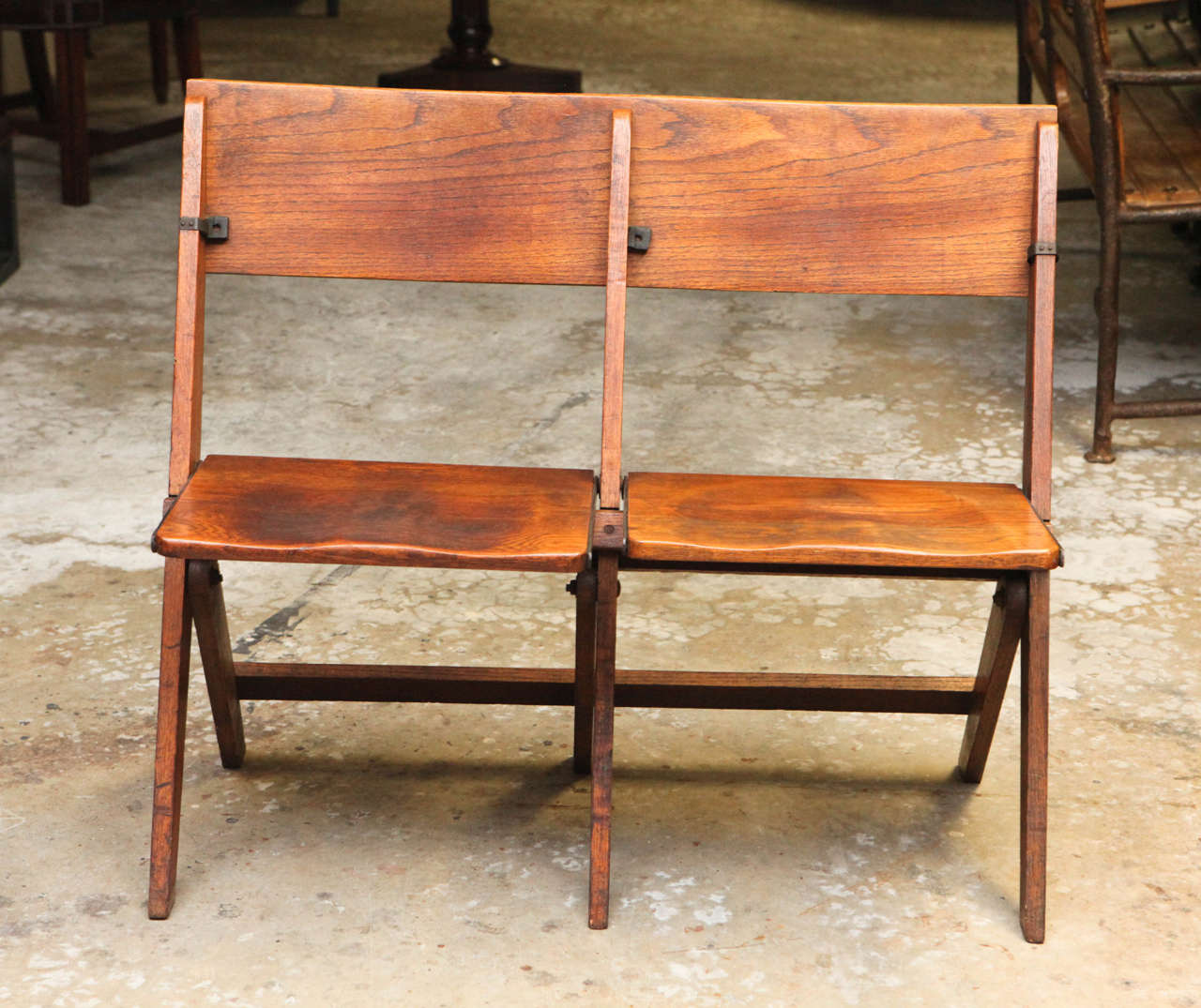 Late 19th-century French double-seated oak folding chair. With small metal structural supports and softly molded seats and back, these chairs blend comfort with utilitarian design, and would make a great addition to an entrance way where occasional