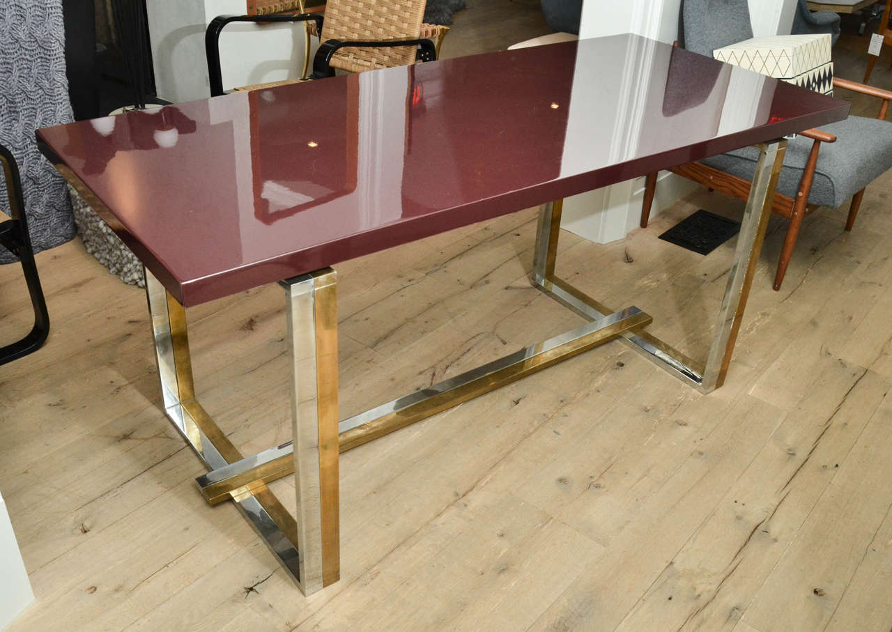 1970s French dining table in the style of Jean Charles with bordeaux lacquered top is supported by a brass and chrome base. Makes for a beautiful dining or meeting room table.
