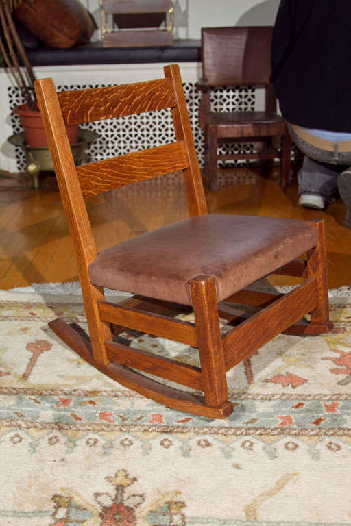 OAK  WOOD CHILD'S ROCKING CHAIR WITH LEATHER SEAT MADE BY GUSTAV STICKLEY IN NEW YORK STATE IN 1905.