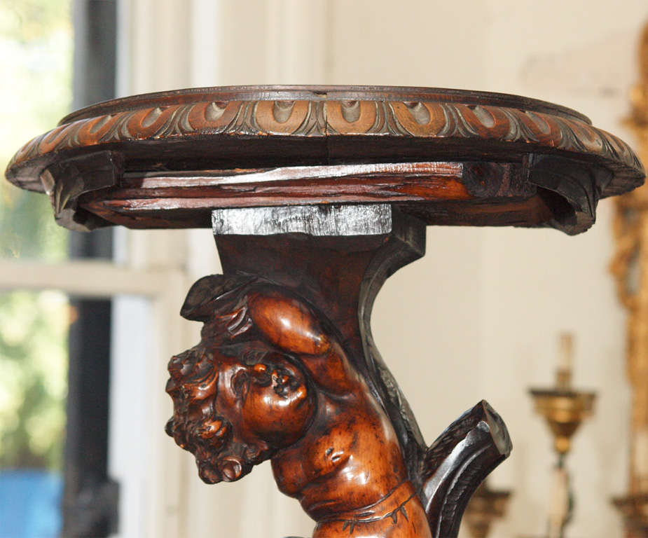 Italian carved walnut stand with three putti cavorting up a tree.