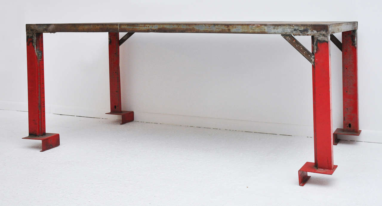 Heavy-gauge steel work/dining table with raw distressed-steel top and red-painted steel legs with steel-flanged stabilizing feet. Once this is secured to your deck or loft floor, it's not going anywhere. Ever.