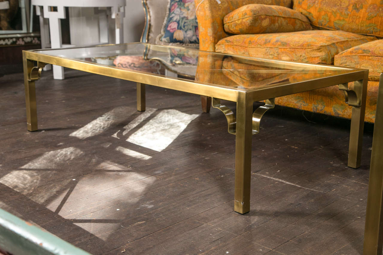 Beautiful rectangular brass Mastercraft coffee table with X-details under glass and fretwork brackets.