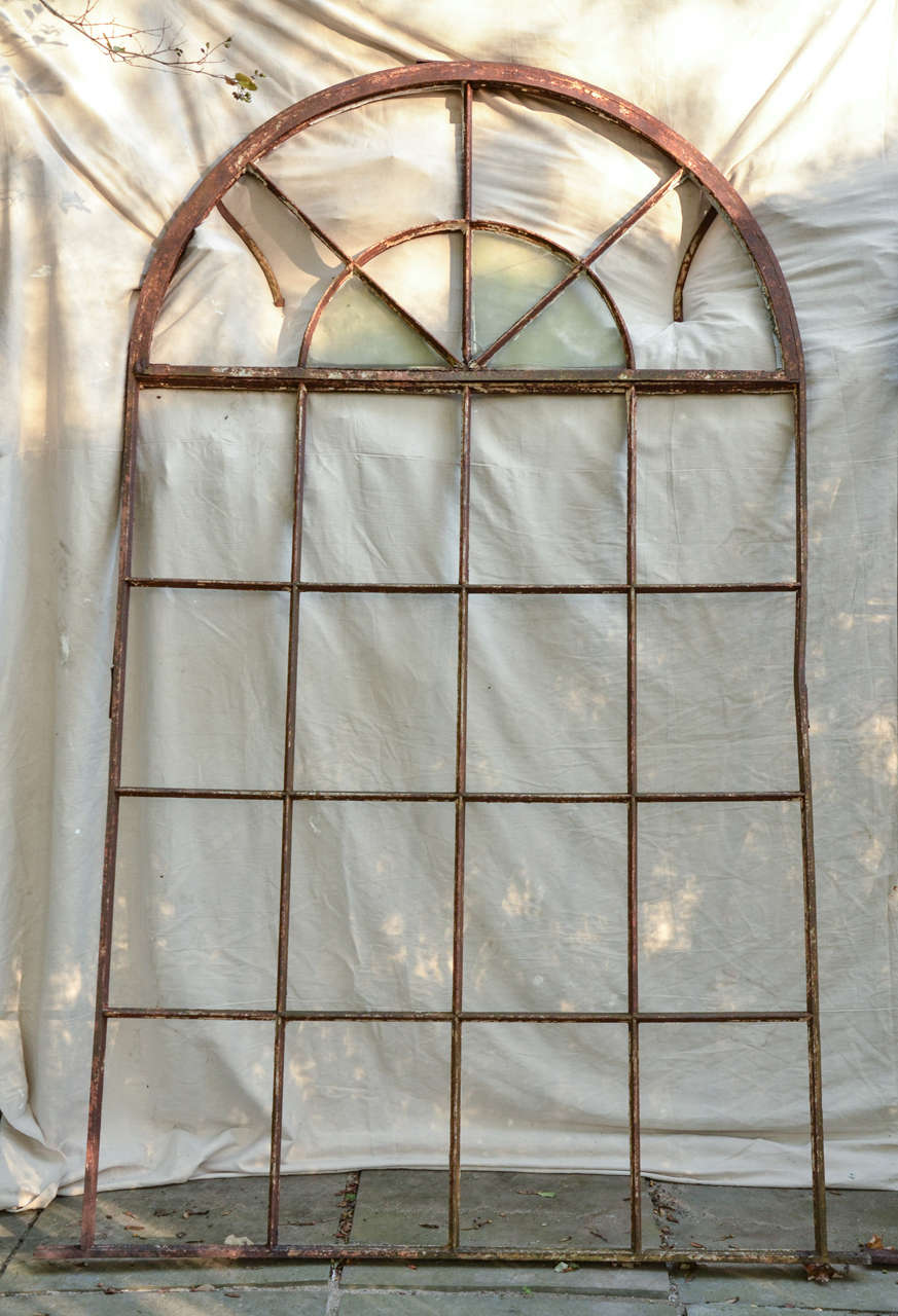 Large English Palladian style cast iron Industrial window frame. Most likely from a Victorian factory or a conservatory. It has finely detailed mullions and a segmented fan light. The brackets on the inside stopped the fan light from falling flat
