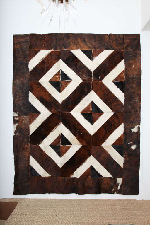 Wonderful rug or wall hanging comprised of individual strips of cowhide sewn together in squares then sewn together crating a diamond pattern. The sides are long rectangular strips of cowhide sewn as a boarder surrounding the squares. This piece is