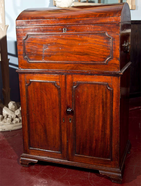 Mahogany two-part cabinet with banded and hinged dome top humidor over a two-door cabinet with single shelf. Reeded, shaped moldings, raised on bracket feet. The humidor with carry handles. The humidor alone measures 19 x 13 x 8 1/2