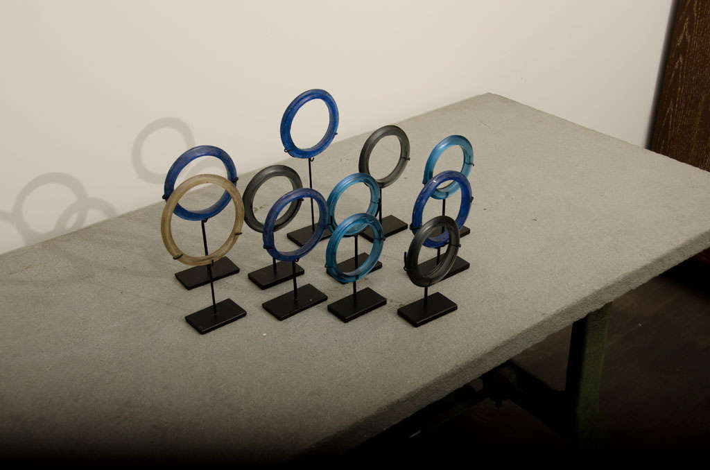 Glass Bracelets in blue tones, grey, + yellow on small metal stands. sizes of rings vary.