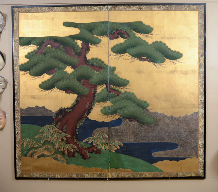 A Japanese folding screen with two panels depicting a landscape scene with a tree in the foreground and lakes and mountains behind.