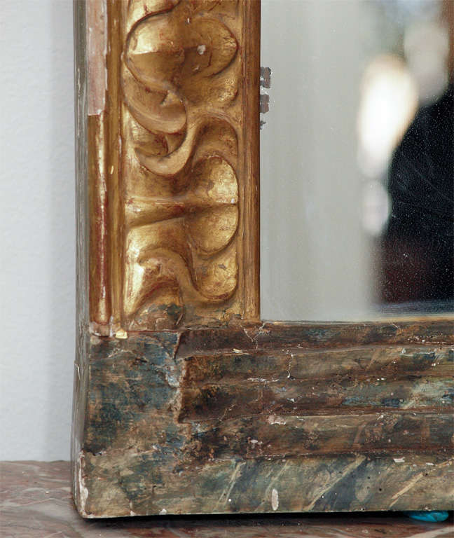 An Italian, giltwood mirror with boldly carved frame resting on a stepped, faux marbled base.