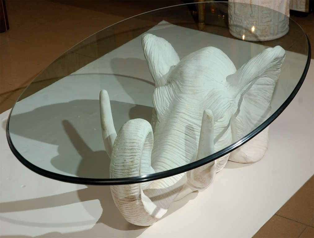 Beveled glass table top sitting on white plaster elephant head.