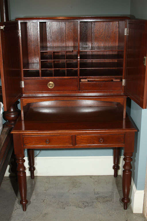 Antique plantation desk with multiple storage cubicles behind doors and two drawers below.