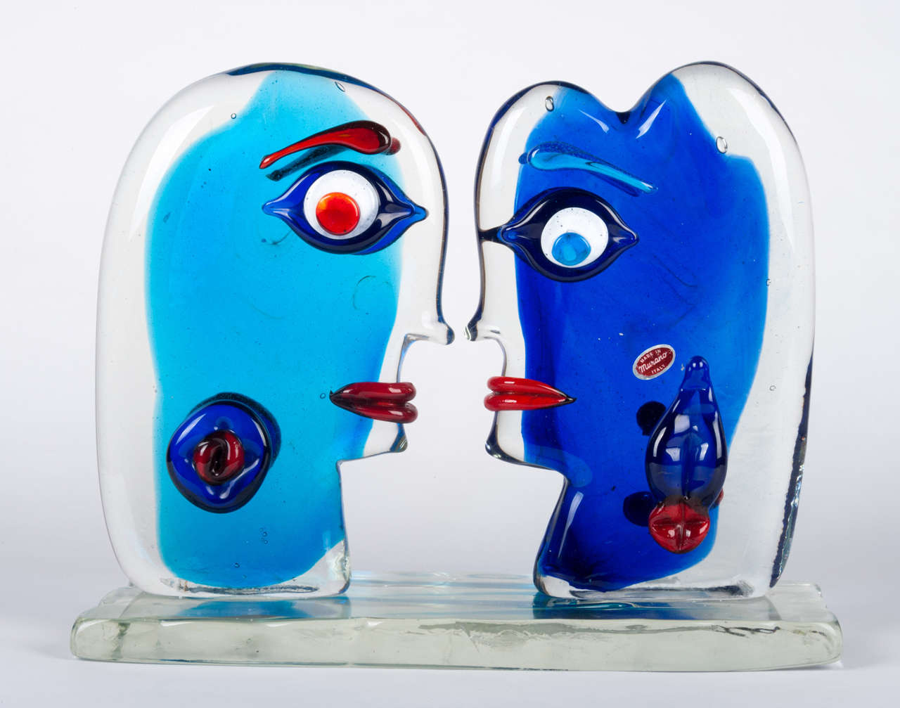 This is a limited edition piece, no 11 of 500, by the Murano glass artist Sandro Frattin, circa 1990.A very heavy piece,it shows a male and a female head set facing each other and modelled in the style of Picasso on a solid clear crystal base. On