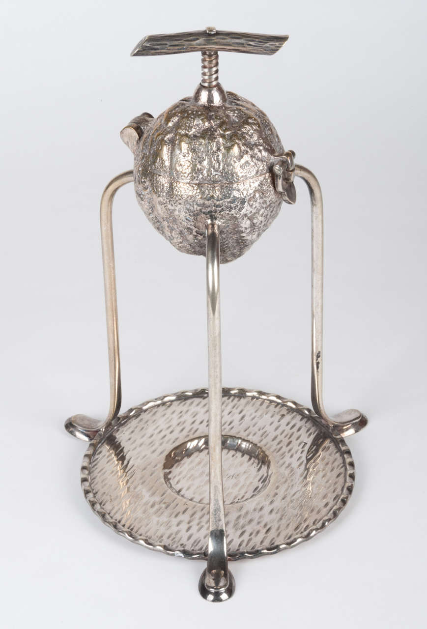 This Silver Plated lemon squeezer is modeled as a lemon in heavy cast metal, with a screw and handle modeled as a wooden log. The tray base bears the makers mark for Hukin and Heath of Birmingham , England and the model number 6010. Both the lemon