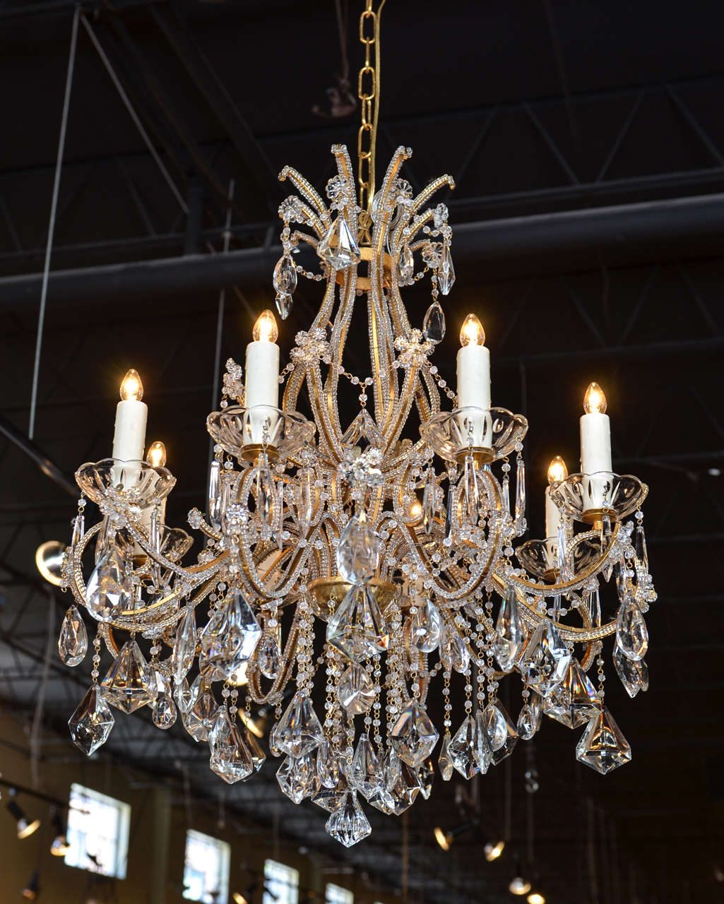 A French Louis XV style eight-light crystal chandelier with gilt metal beaded armature from the 19th century. This French crystal chandelier features a nicely curved armature supporting eight scrolled arms. Delicately adorned with rosettes, this