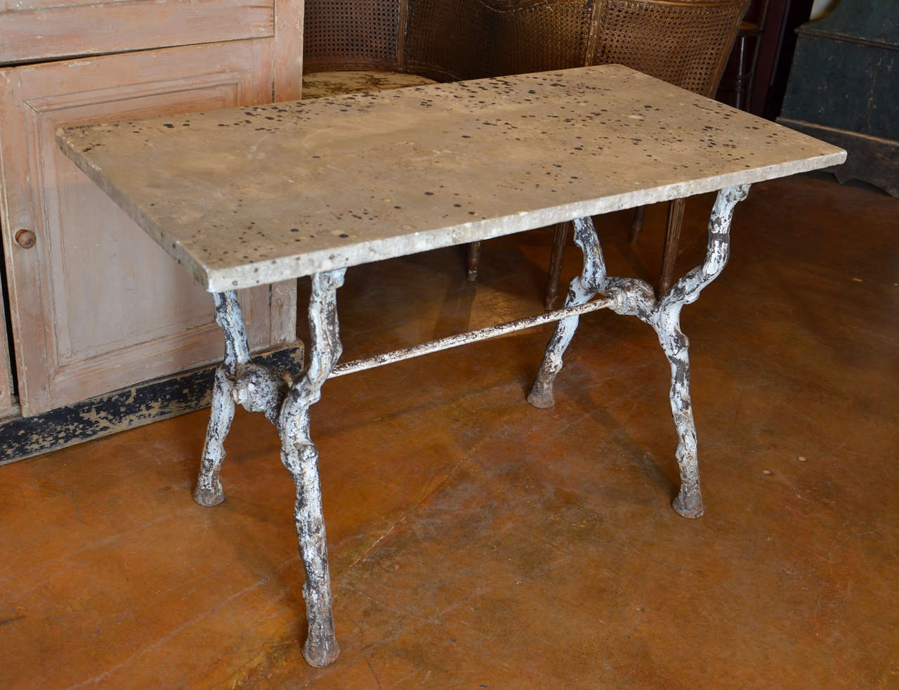 A French marble-top and faux-bois garden table from the 19th century. The table features a simple rectangular marble top over a faux-bois base. The trestle base is made of branch-like legs forming an X-shape and connected to each other with a cross