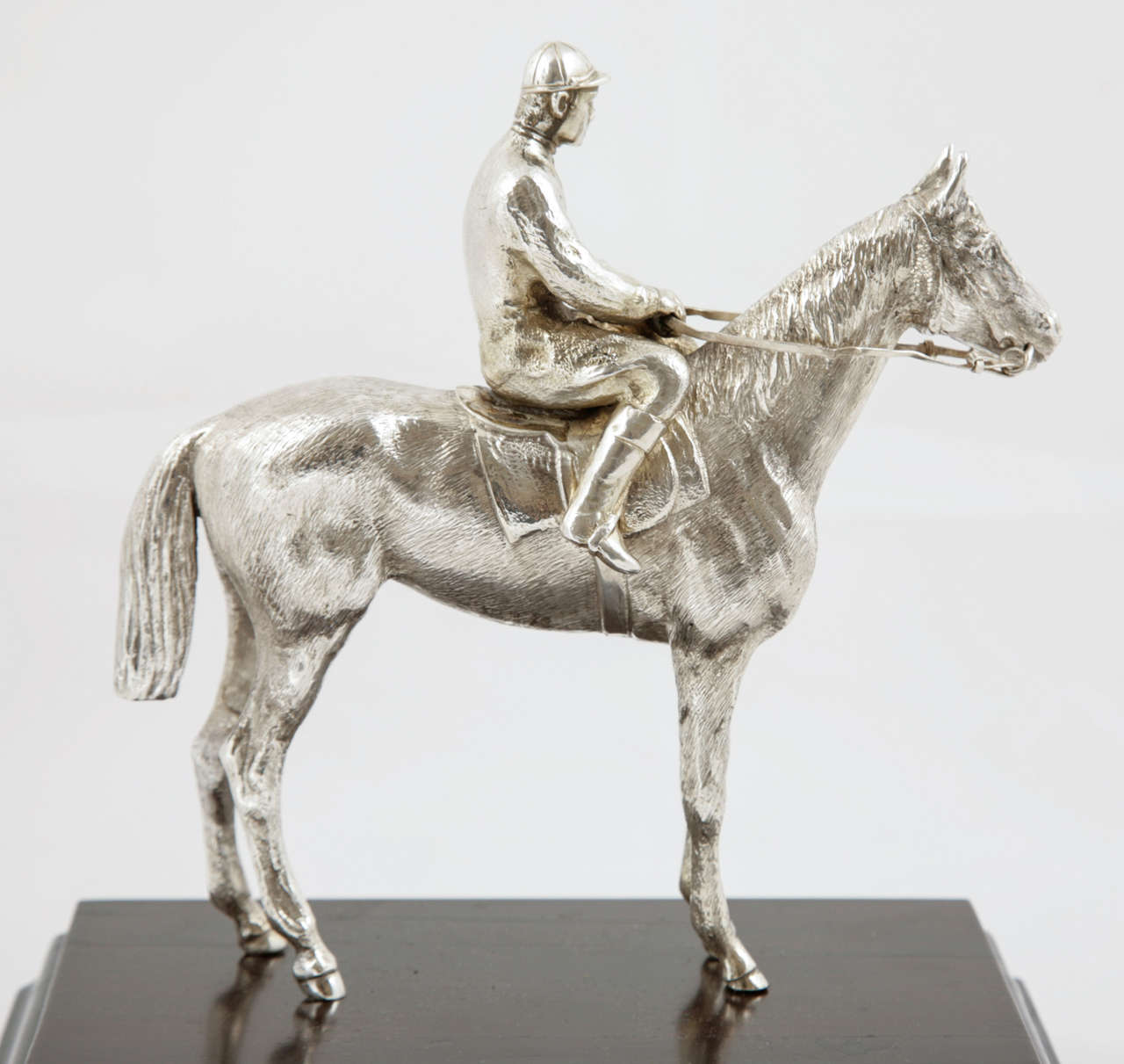 A sterling silver model of a racehorse and jockey mounted on a mahogany plinth.
The attention to detail of this lovely trophy is very good and it is hallmaked London 1973. The height including the plinth is 19.7cms; and the lenghth of the base is