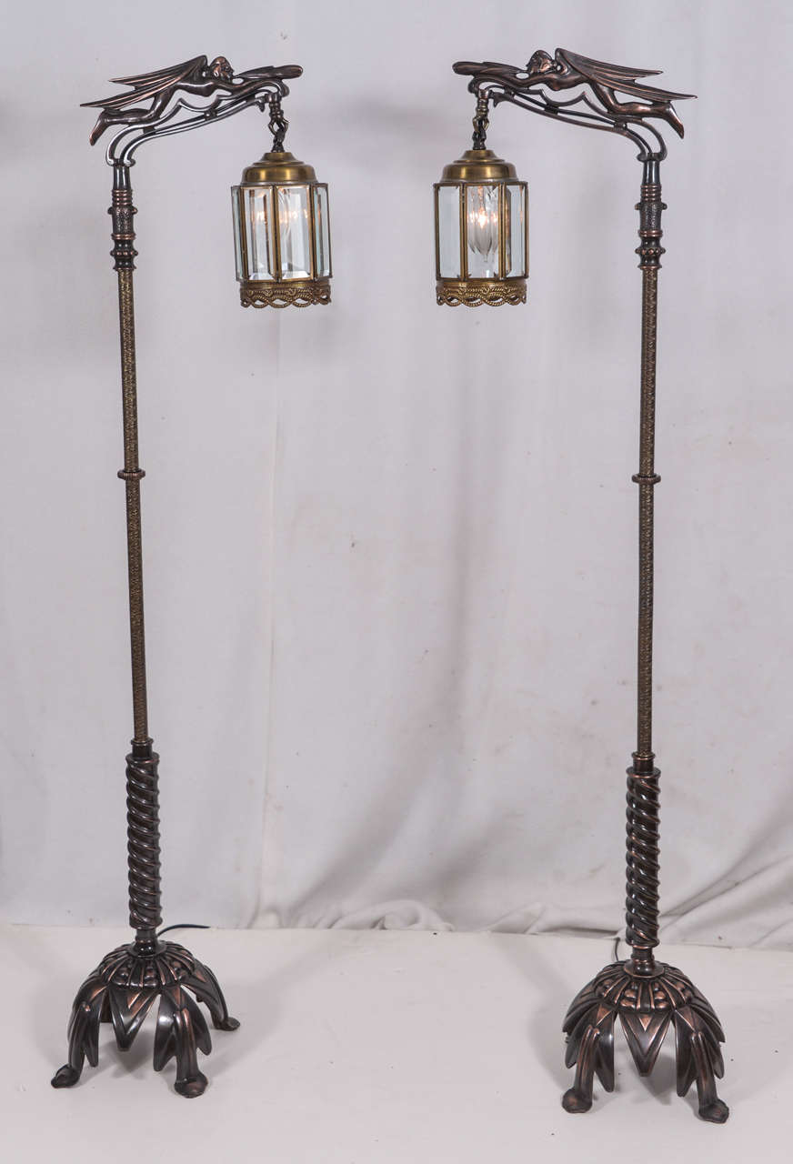 Pair of cast iron vintage Rembrandt floor lamps with a decorative stem and a domed, decsix panel beveled glass lanterno-style base on four supports. Along top of each lamp, supporting the six panel beveled glass lantern, is the image of an angel