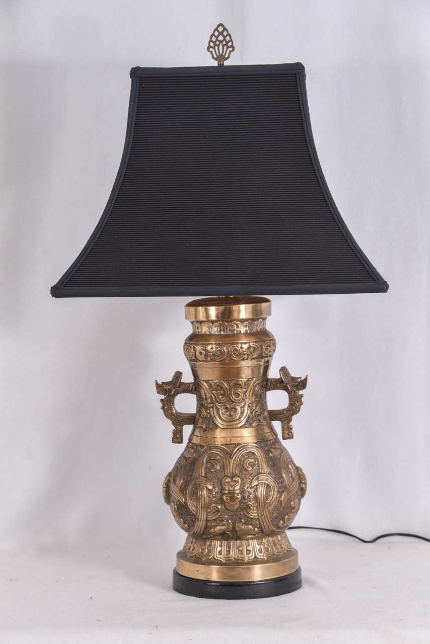 Pair of Bronze, Asian temple jars as table lamps. Ornate raised design on the cast bronze, mounted on a custom base. Height to bottom of socket is 19".  Overall height with shade is 32".  Priced without lamp shades. Lampshades shown are