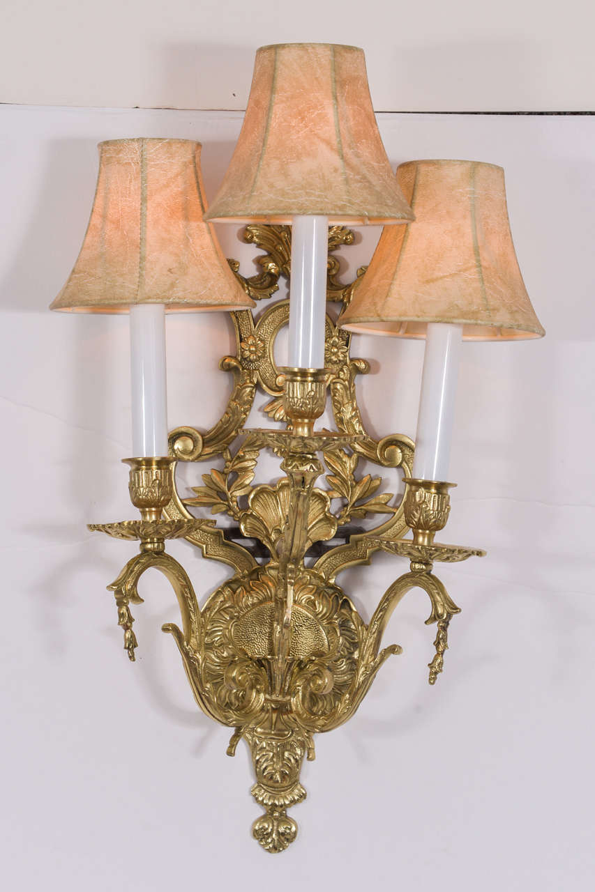 French, polished brass, three-light sconces with floral motif. 1960s totally restored and rewired. Ready to install. Shown with faux skin shades. Priced without shades. Shades $38.00 each.