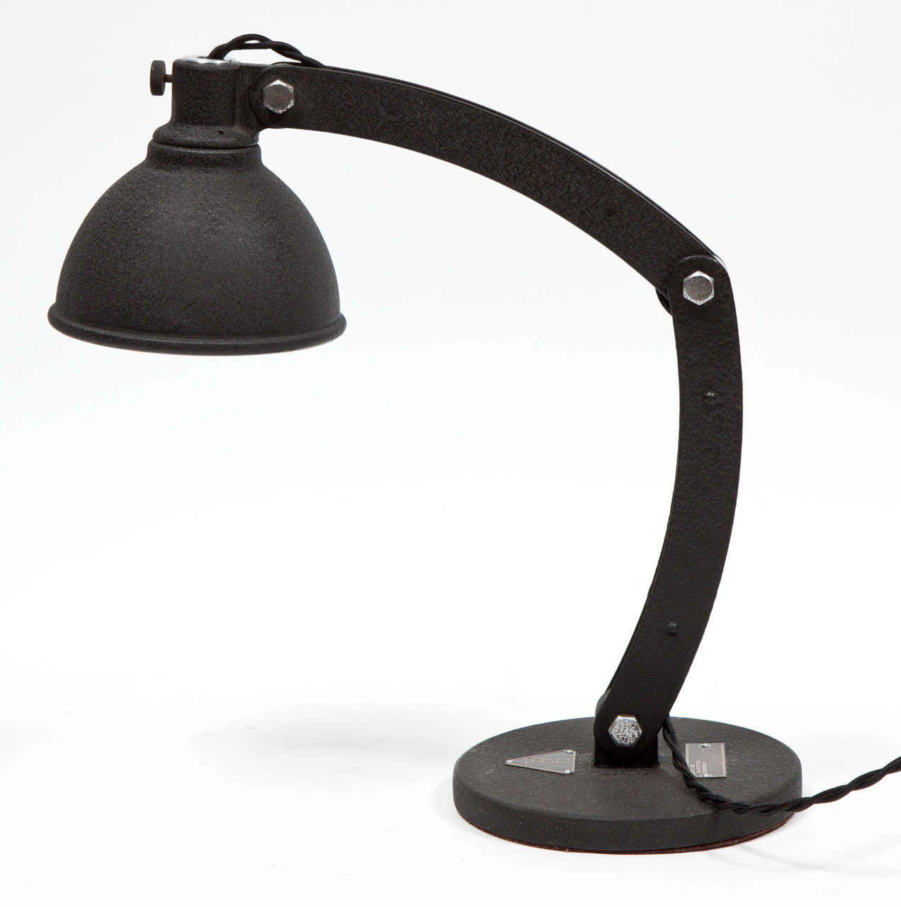 Task lamp with textured black metal finish by Bausch & Lomb.  Signed with metal label on base.  USA, circa 1930.  Fully adjustable, three-jointed arm resting on round base with mirror interior reflector.