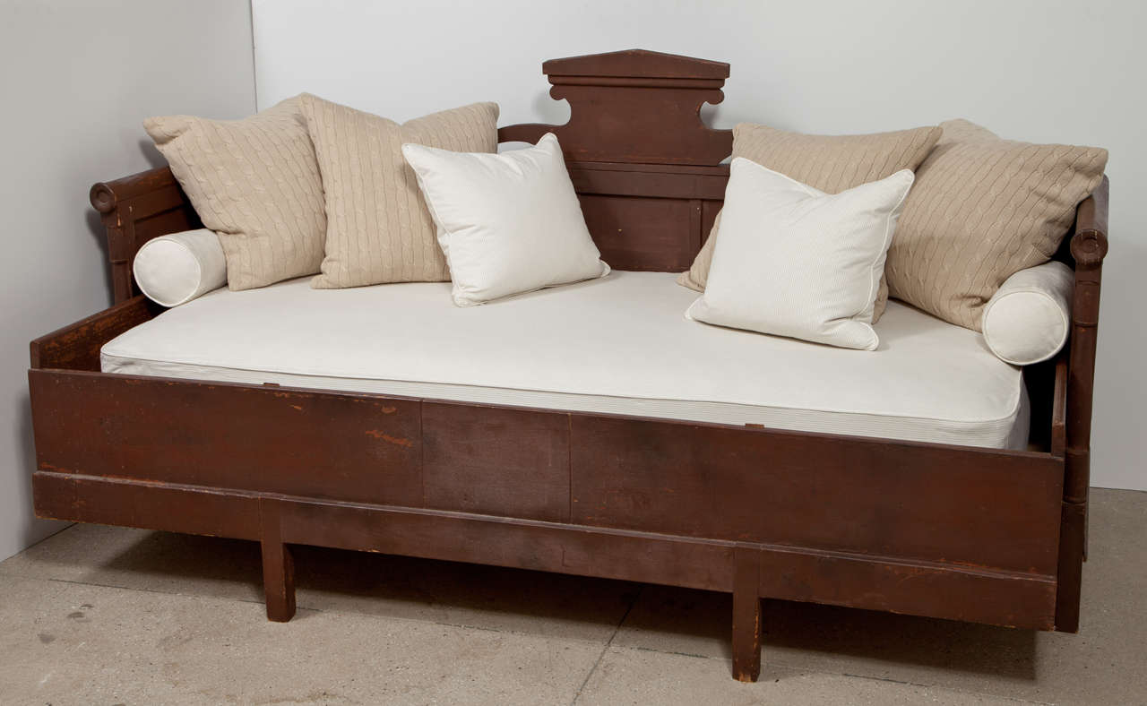 Antique Swedish painted bed with a twin size mattress newly upholstered in a neutral ticking fabric.
All the assorted pillows are included (six) and (two) bolsters.
The paint color is a rustic red, brown.
Arm height is 32 1/2
