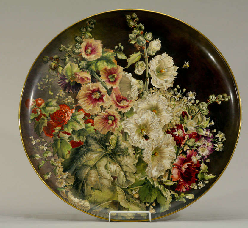 This is a fabulous Minton museum quality hand-painted charger or plaque, realistically depicting hollyhocks and leaves with the associated insects and wildlife. The brown enamel background provides a dramatic contrast to the vibrant and